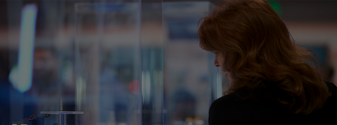 Red haired woman looking through a glass at a product